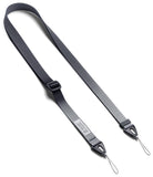 Design Shoulder Strap - A clear phone case with a black shoulder strap resting on an open book with other colorful straps.