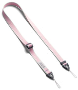 Design Shoulder Strap - A smartphone in a clear case attached to a grey adjustable shoulder strap resting on an open book.