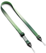 Design Shoulder Strap - Woman wearing a green phone shoulder strap with a clear case in a park setting.