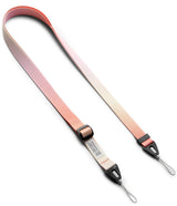 Design Shoulder Strap - Person wearing a pink-to-white gradient phone strap attached to a clear phone case while walking outdoors.