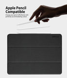 Smart Cover Apple Pencil Stand | iPad - A black textured tablet case shown on a light gray background, with three white stylus pens floating above it. A human hand is visible holding one stylus, and text at the top reads 'Apple Pencil Compatible' with a smaller explanatory line.