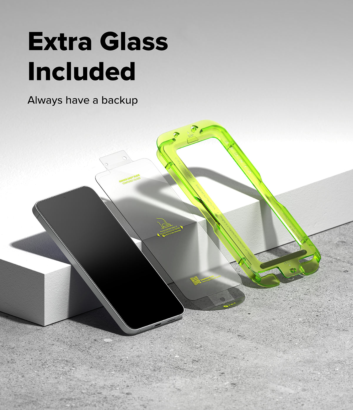 Galaxy S26 FE Screen Protector | Easy Slide Tempered Glass (2P) - A smartphone shown with two transparent screen protectors, one lying flat and one standing upright in a bright translucent green frame. Large text at the top reads 'Extra Glass Included' and 'Always have a backup' on a clean white-to-gray studio background.