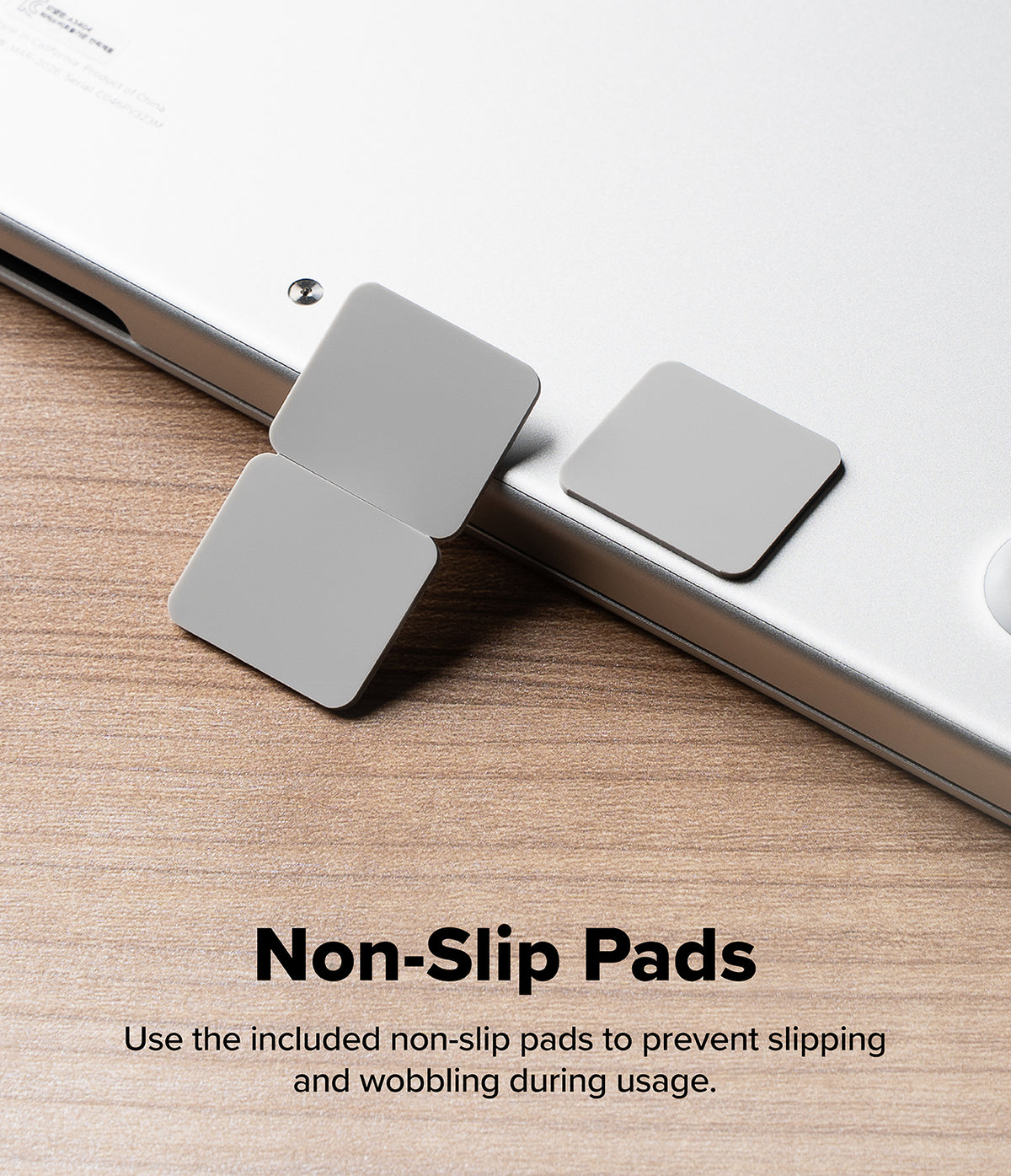 Step-Fit Mini Stand - Three square silver non-slip pads shown on a closed silver laptop, placed on a wooden surface, with the text 'Non-Slip Pads' and a usage note below.