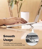 Step-Fit Mini Stand - A silver laptop stand supporting an open silver laptop on a wooden desk, with a person's hand resting on the keyboard. Text reads 'Smooth Usage' and 'TPU-lined stand ends provide a smoother, more comfortable feel.